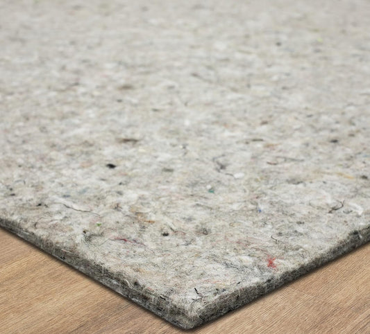 A rectangular gray pad lies flat, displaying a mottled, fibrous surface and a rounded corner resting on a light wooden floor.